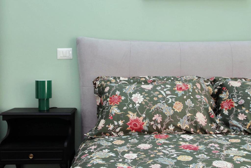 Una cama con una almohada floral y una lámpara en una mesita de noche. en Neo Urbis Art Aparts, en Roma