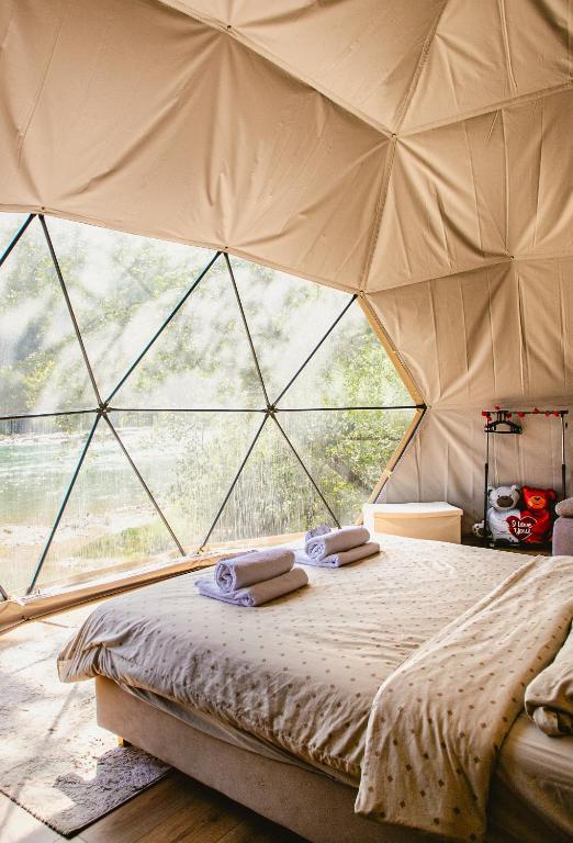 a bedroom with a large window with towels on a bed at Glamping Drina Riverzone in Goražde