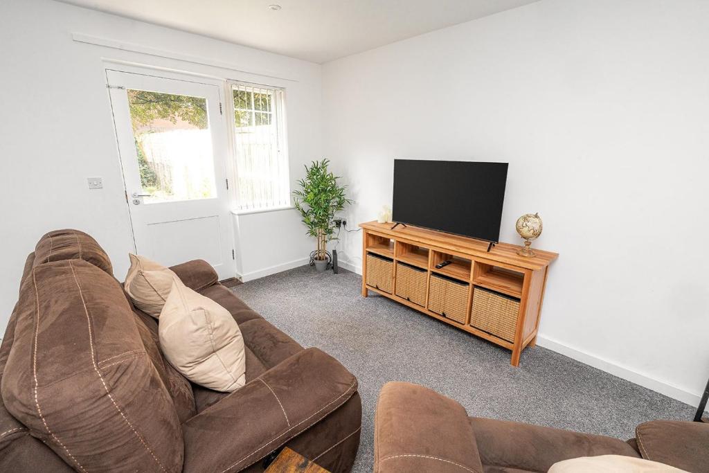 a living room with a couch and a flat screen tv at Modern 2-Bed Home with Driveway – Basingstoke in Sherborne Saint John