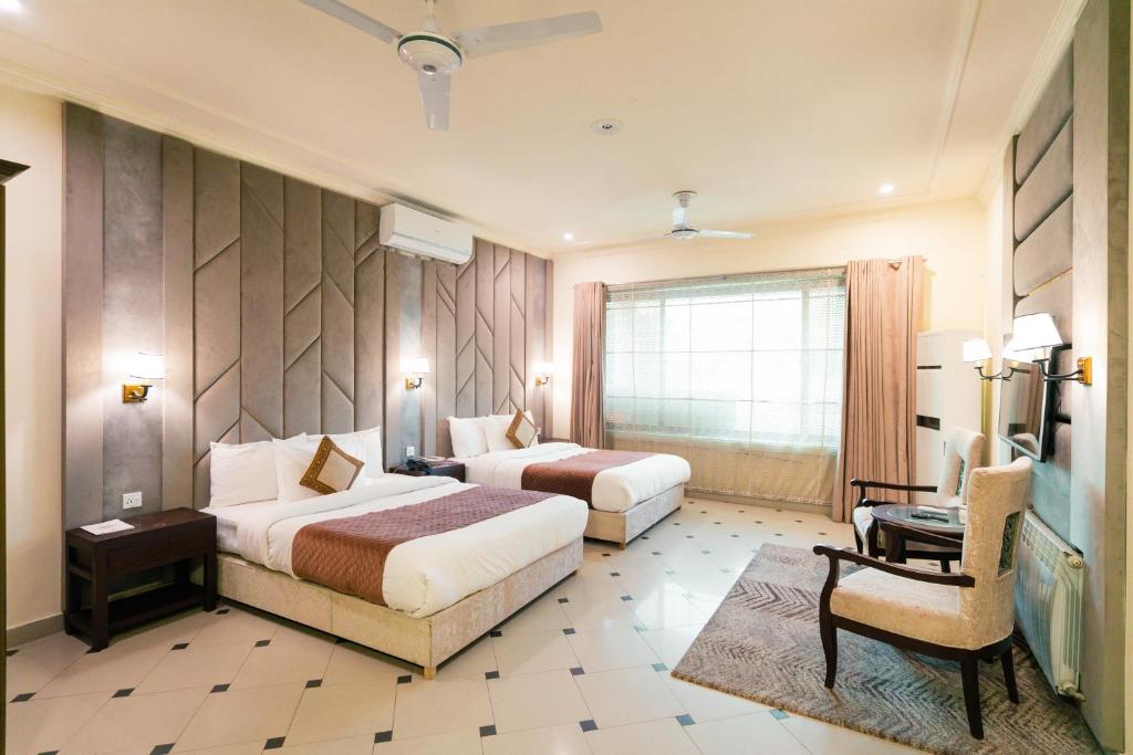 a hotel room with two beds and a chair at Shelton Rezidor Jinnah Super in Islamabad