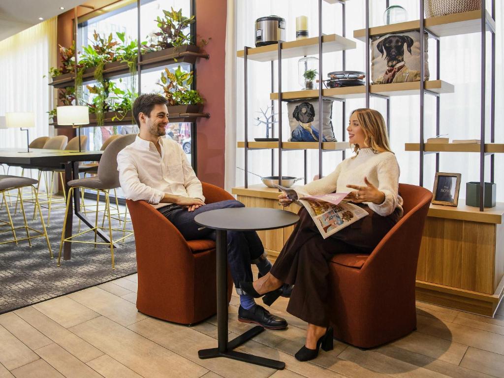 a man and woman sitting in chairs at a table at Aparthotel Adagio Muenchen City in Munich