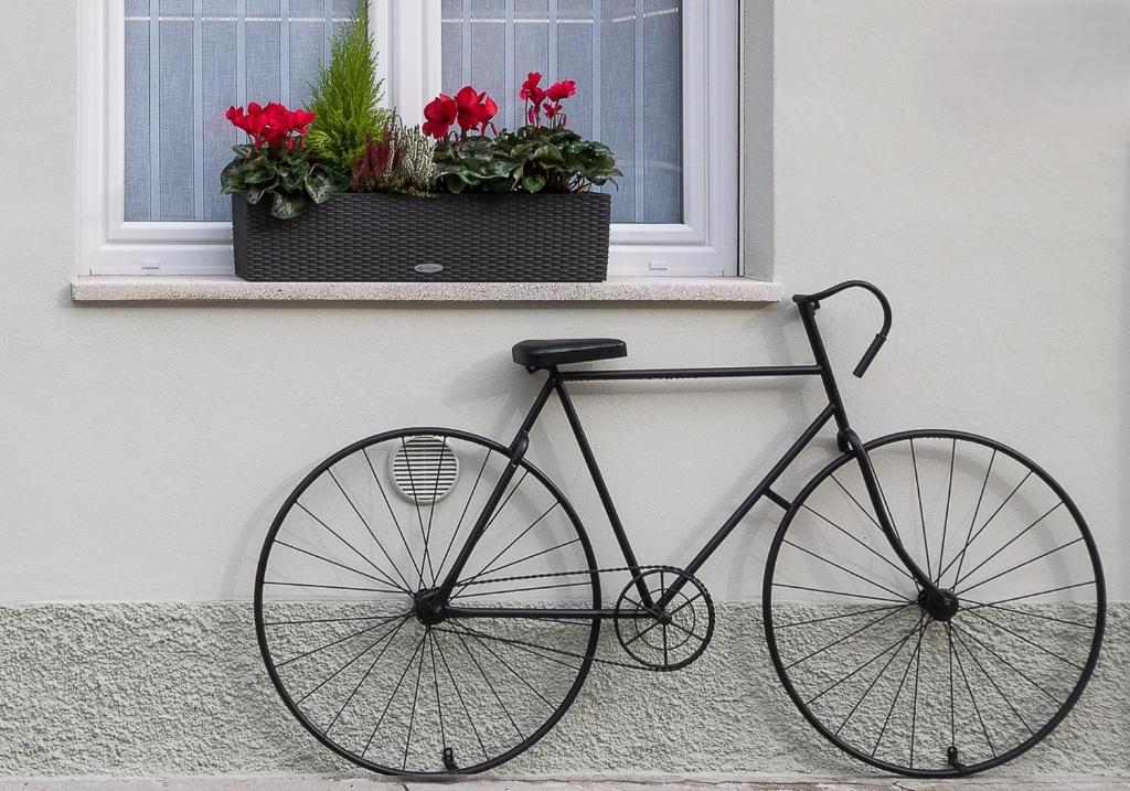 a bike is parked under a window with flowers at ZONA 30 Bike Guesthouse in Palmanova