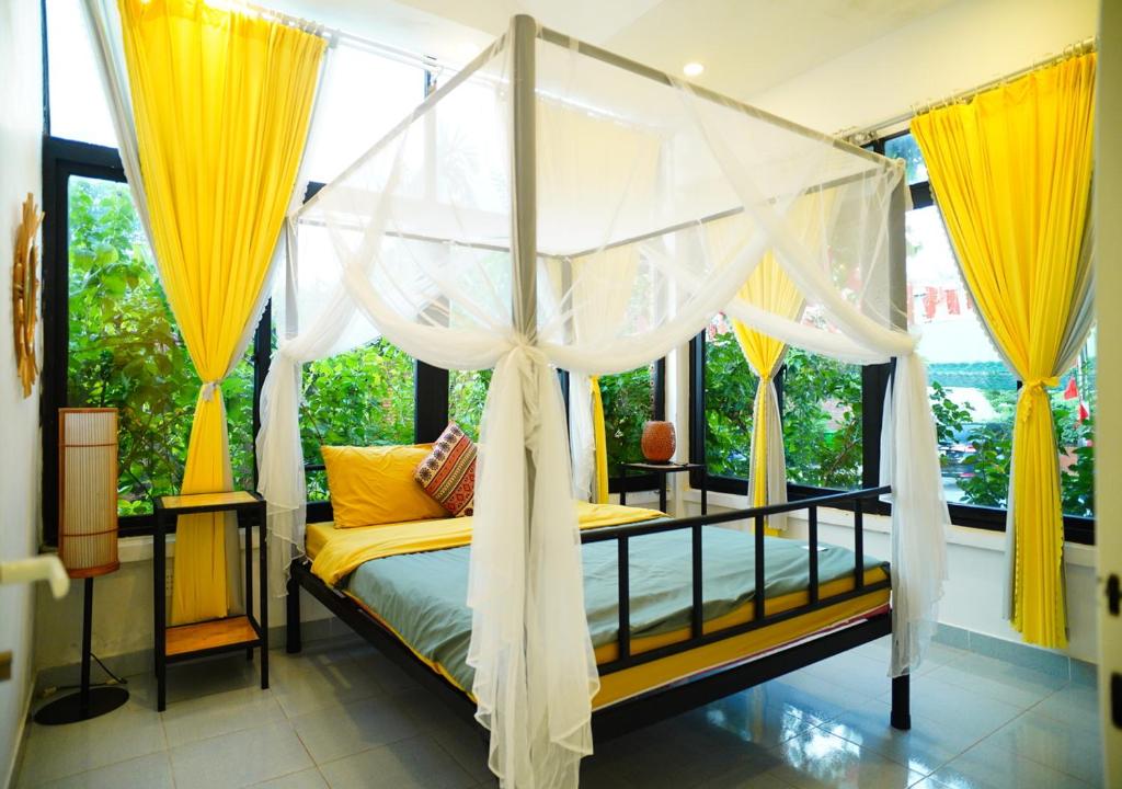 a bedroom with a canopy bed with yellow curtains at Vườn Thủ Đô Homestay in Buon Ma Thuot