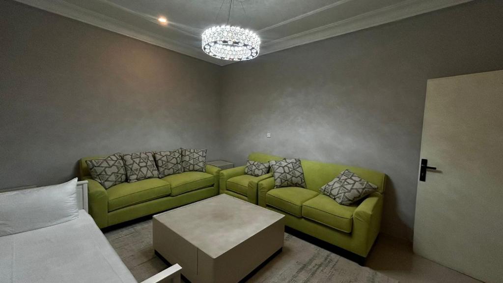Una sala de estar con un sofá verde y una mesa. en شقة الزهور, en Al Nairyah