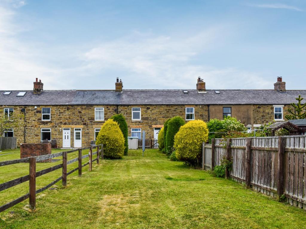 an old brick house with a wooden fence at Old Port Cottage in Hinderwell