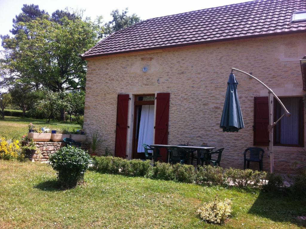 a house with a table and an umbrella in the yard at Gite Périgourdin - 3 Chambres in Labrousse