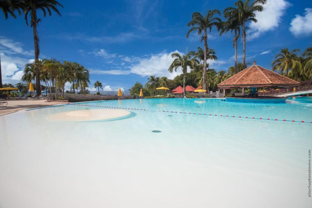 een groot zwembad in een resort met palmbomen bij Au beau village studio vue nature in Sainte-Luce