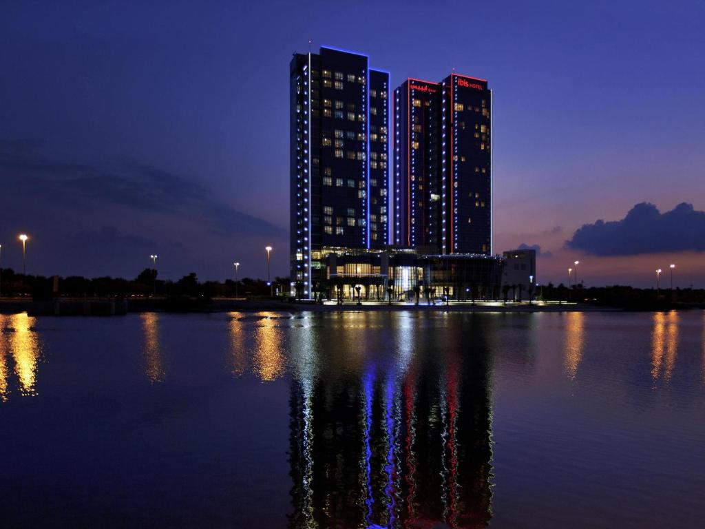 Un gran edificio con luces en el agua por la noche. en Ibis Abu Dhabi Gate, en Abu Dabi