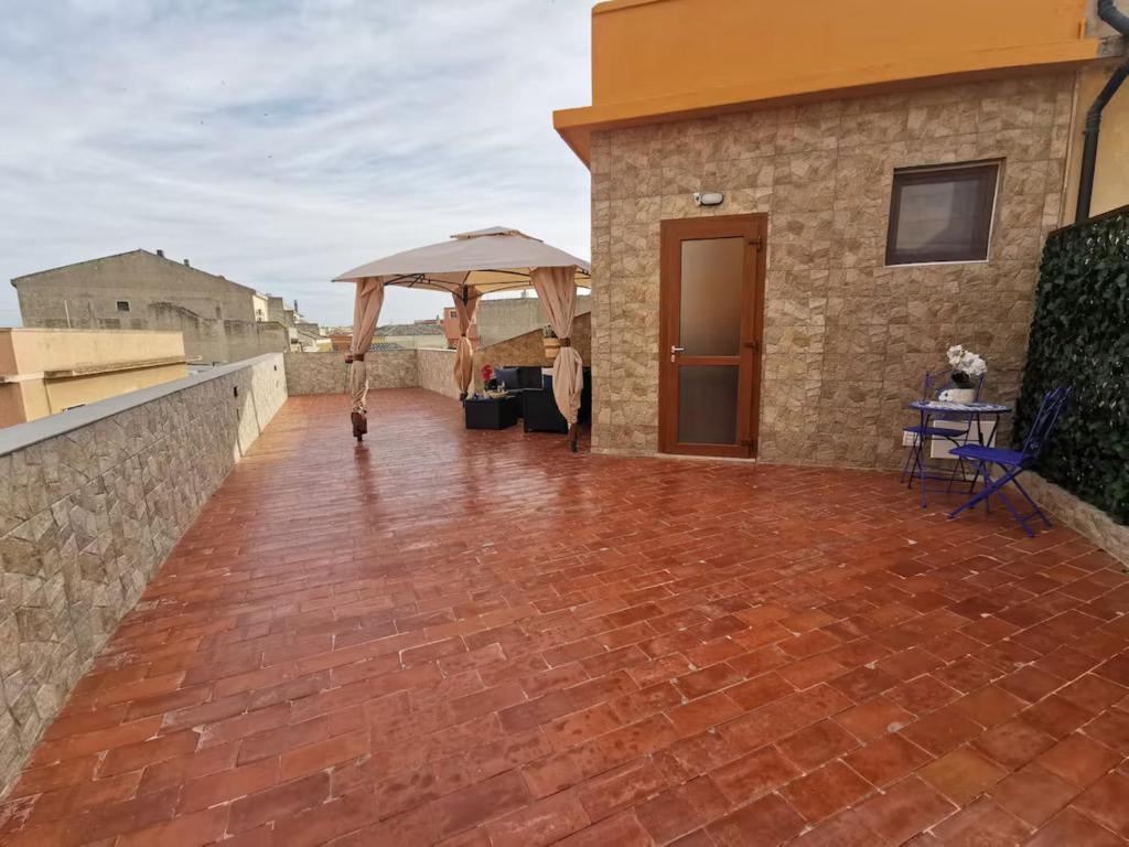 クアルトゥ・サンテーレナにあるSa Domu de Aury - 5 minutes from Poetto Beachのレンガ造りのパティオ(建物の上に傘付)