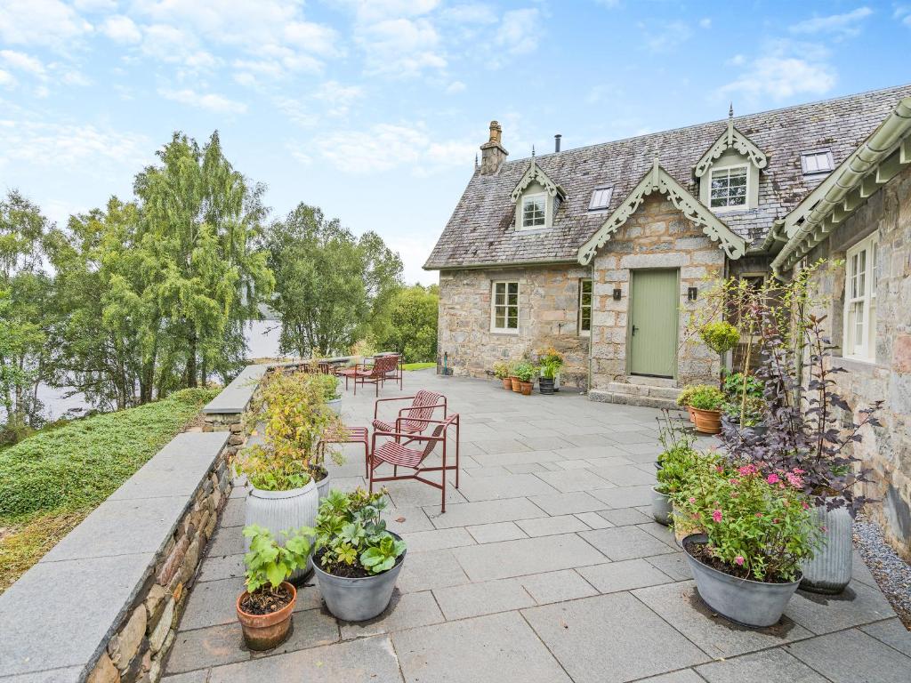 a stone house with potted plants on a patio at Uk47812 - Wardens Cottage in Kinloch Rannoch