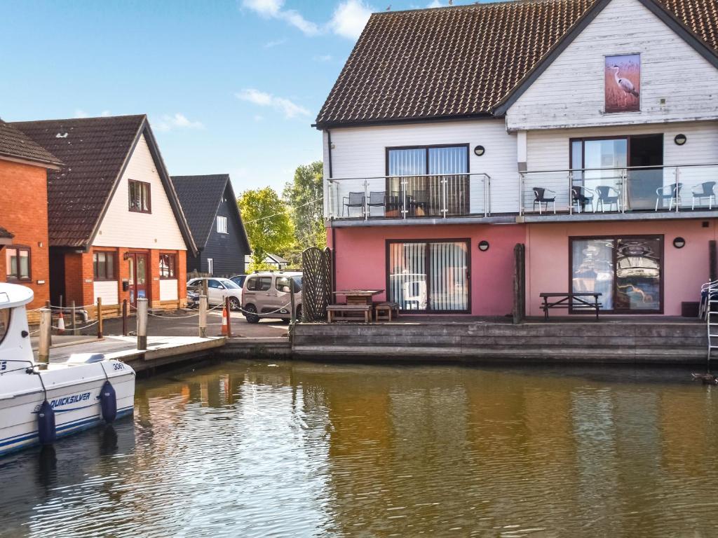 een huis naast een rivier met een boot bij Swift Cottage in Horning