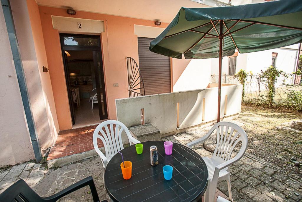 Una mesa negra con una sombrilla verde y sillas. en Cozy apartment near the beach, en Rosolina Mare