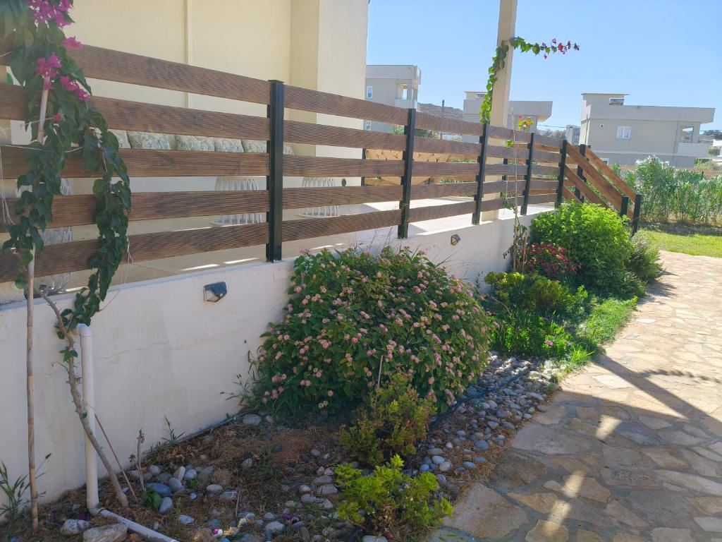 a fence next to some bushes and flowers at Sandy Ridge in Kalamaki Heraklion