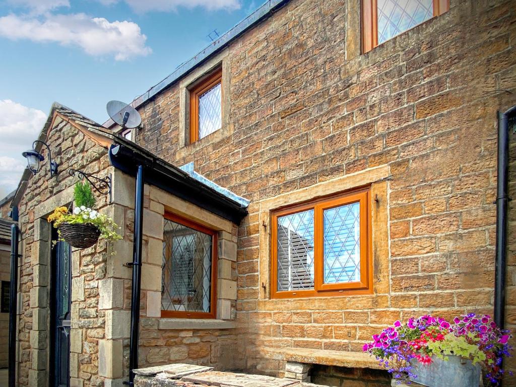 a brick building with windows and flowers on it at Weavers Cottage in Barrowford