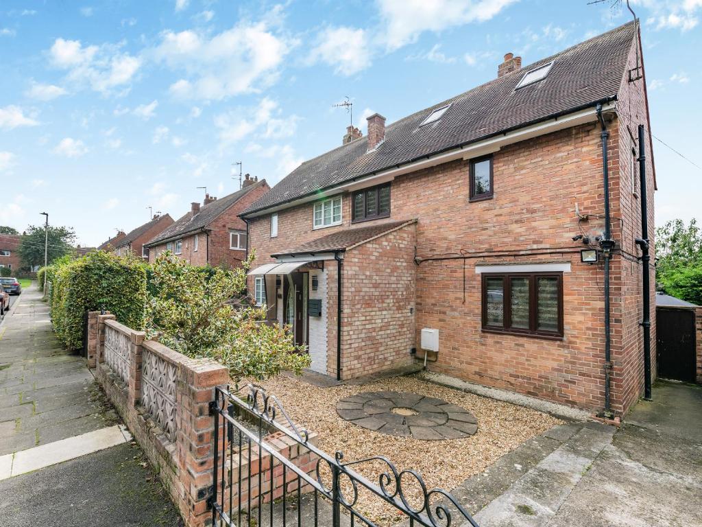 a brick house with a fence in front of it at Cherrytrees in Scarborough