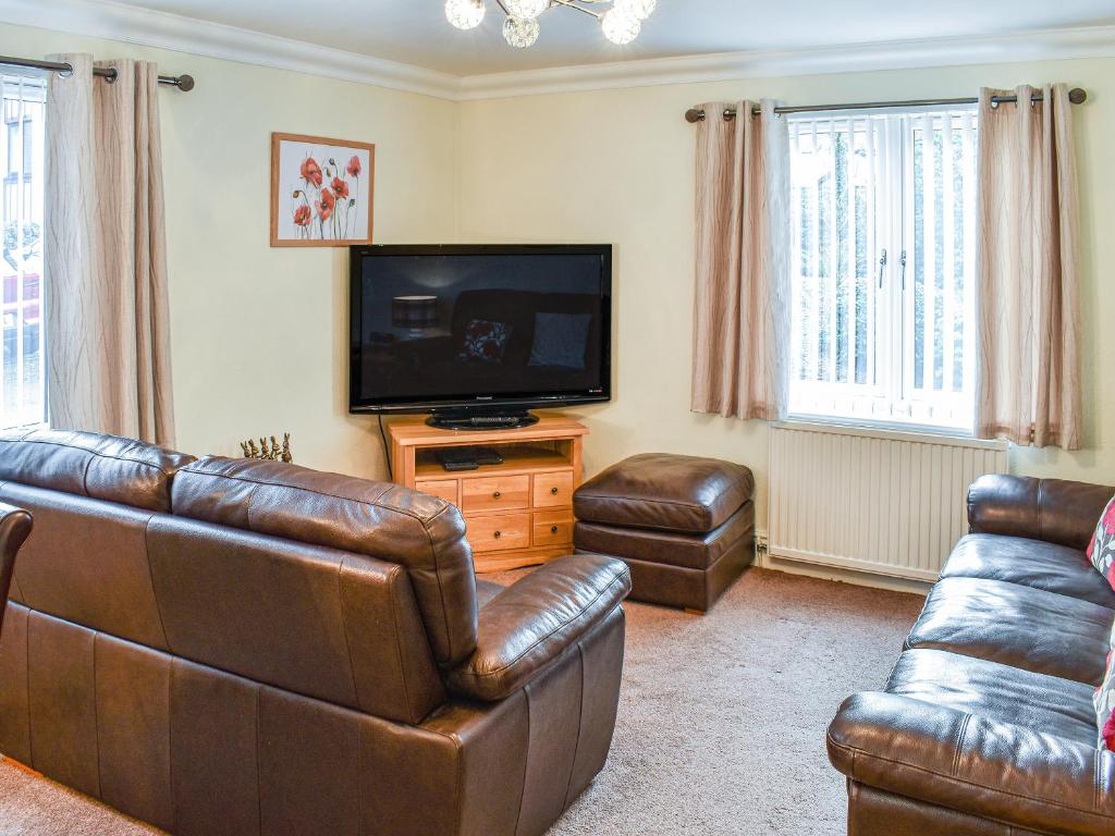 a living room with leather furniture and a flat screen tv at 7 Oaklands in Ambleside