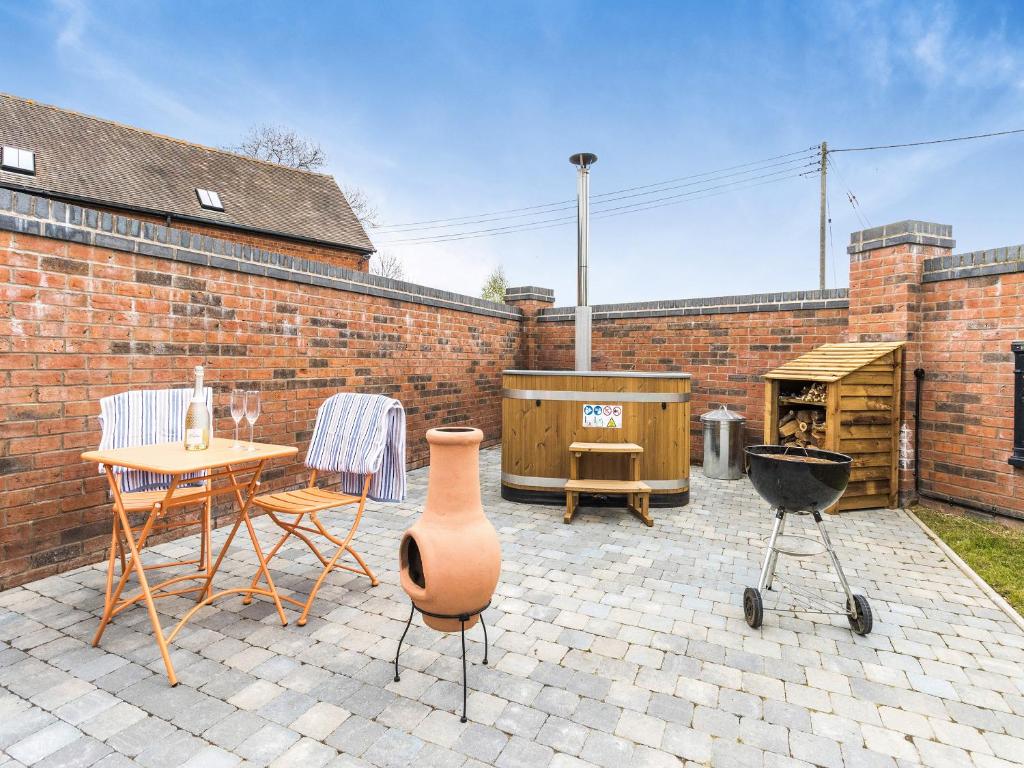 Un patio con parrilla y mesa y sillas. en The Little House - Uk49129, en Stapleton