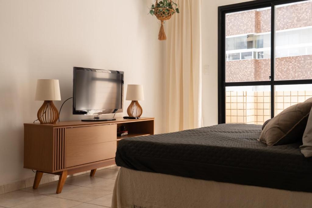 a bedroom with a bed and a flat screen tv at Apartamento completo com garagem a 150 m da praia in Praia Grande