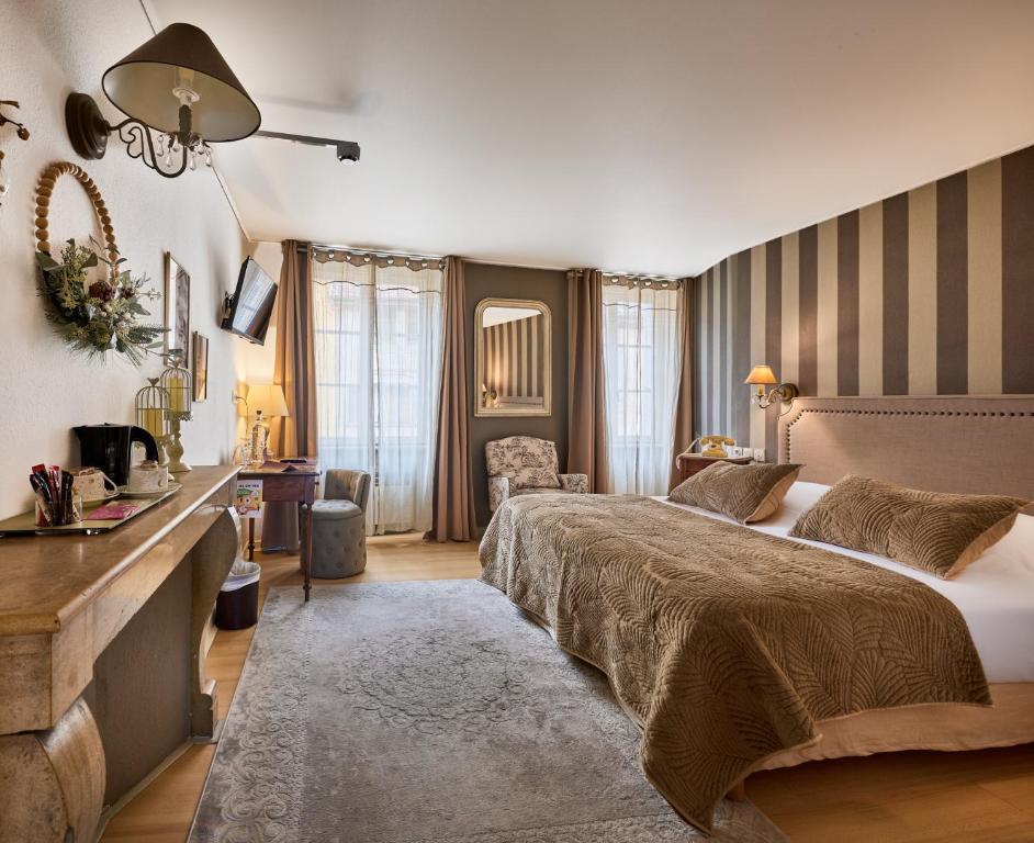 a bedroom with two beds and a living room at The Originals Boutique, Hôtel de la Balance, Montbéliard in Montbéliard
