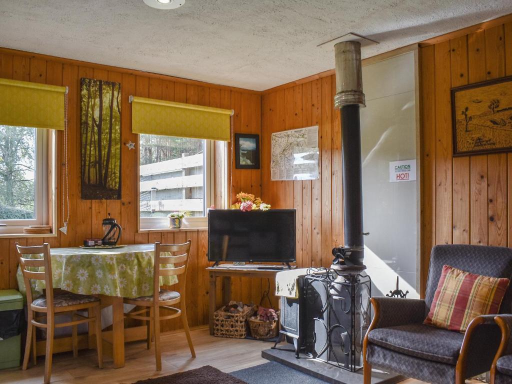 a living room with a stove and a table and a television at The Bothy - Ukc5785 in Nethy Bridge