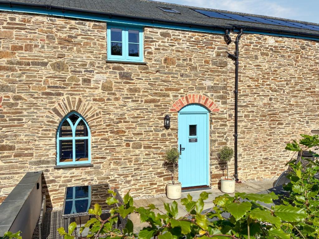 a brick building with a blue door and two potted plants at Lavender Cottage -Uk49209 in Jacobstowe