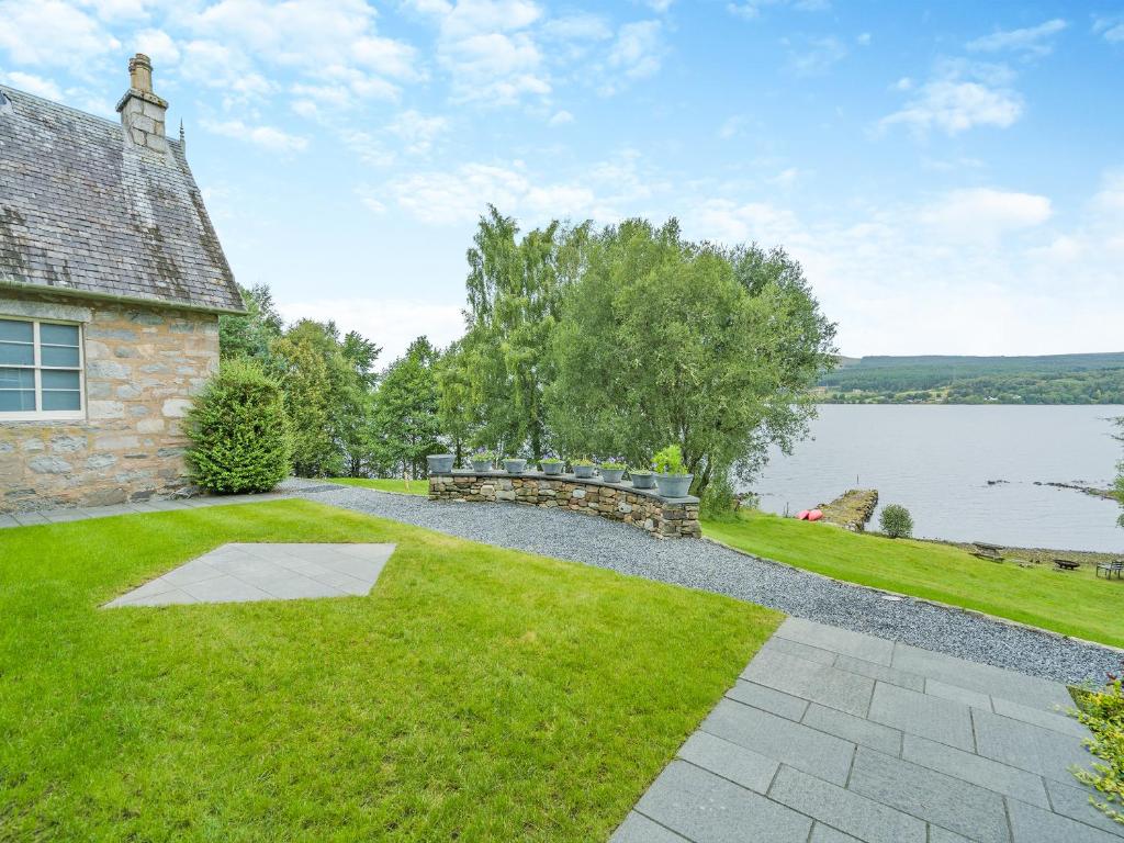 une maison en pierre avec une cour herbeuse à côté d'un lac dans l'établissement Uk47813 - Cooks Cottage, à Kinloch Rannoch