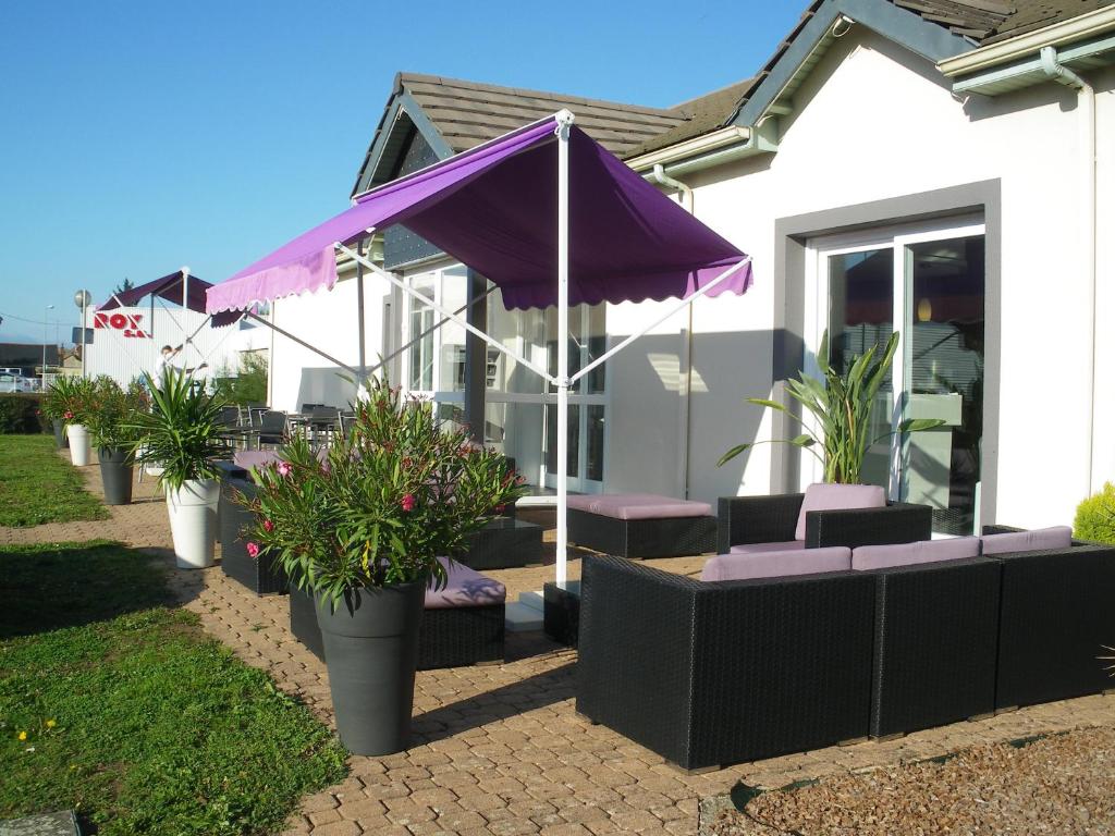 un parasol violet, des chaises et des plantes devant une maison dans l'établissement The Originals City, Hôtel La Terrasse, Tours Nord (Inter-Hotel), à Tours