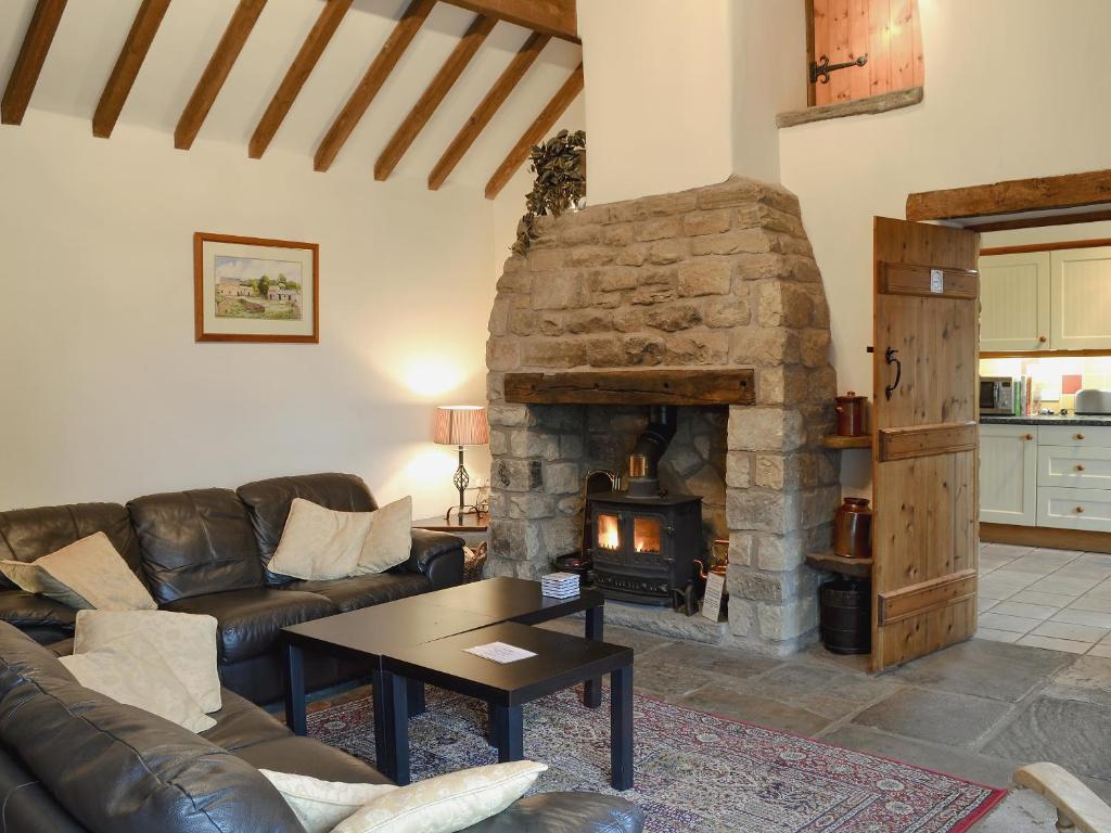 a living room with a stone fireplace and couches at Spring Cottage in Hollinsclough