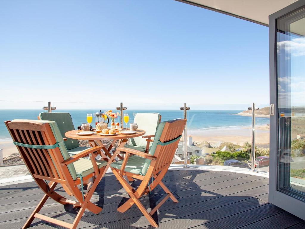 einen Tisch und Stühle auf einer Terrasse mit Meerblick in der Unterkunft Soft Sands - Cottage in Woolacombe