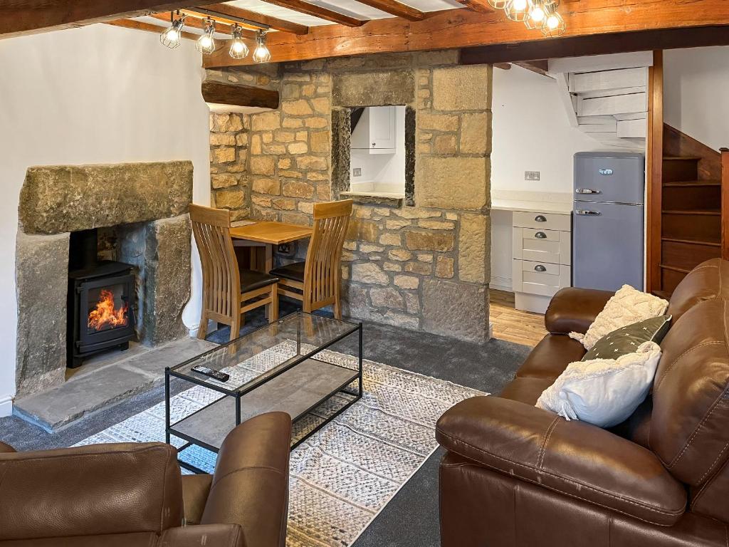 a living room with a couch and a fireplace at Candy Cottage in Addingham