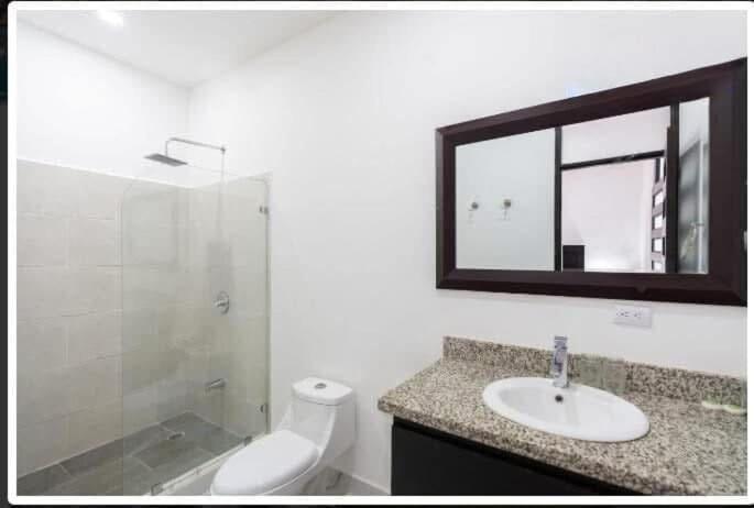 a bathroom with a toilet and a sink and a mirror at Havana Jaco in Jacó