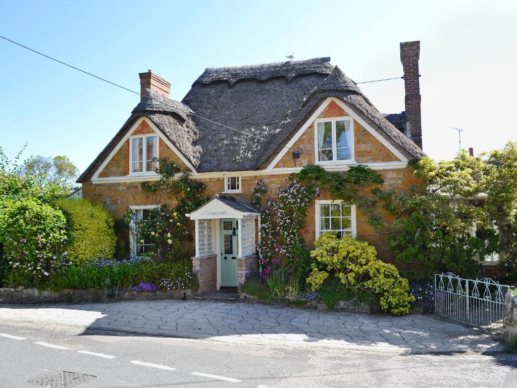 a brown brick house with a black roof at Swiss Cottage in Chideock