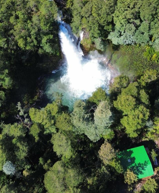 an aerial view of a waterfall in a forest at Cabaña Refugio Cascada in Llanada Grande