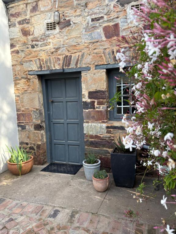 ein Steingebäude mit blauer Tür und einigen Pflanzen in der Unterkunft Oatlands Cottages in Grahamstown