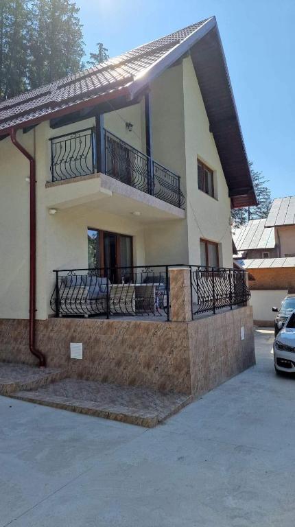 a house with a balcony and a car parked in a parking lot at Vila Cantacuzino in Buşteni