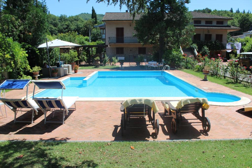 una piscina con 2 sillas y una casa en B&B Elda Country House, en Chiassa Superiore
