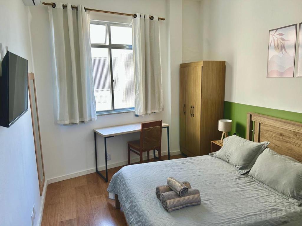 a bedroom with a bed with a desk and a window at Flat encantador no Centro do Rio de Janeiro in Rio de Janeiro
