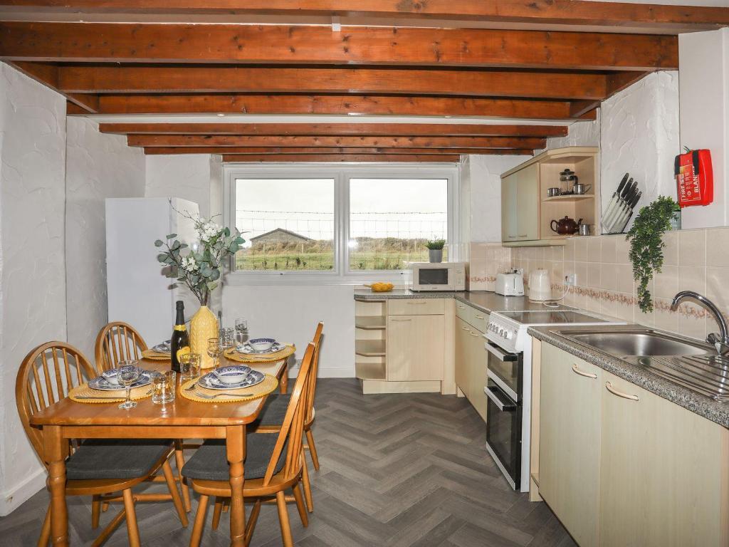 a kitchen with a wooden table and a table and chairs at Fadrun - 3 Ty'n Don in Pwllheli