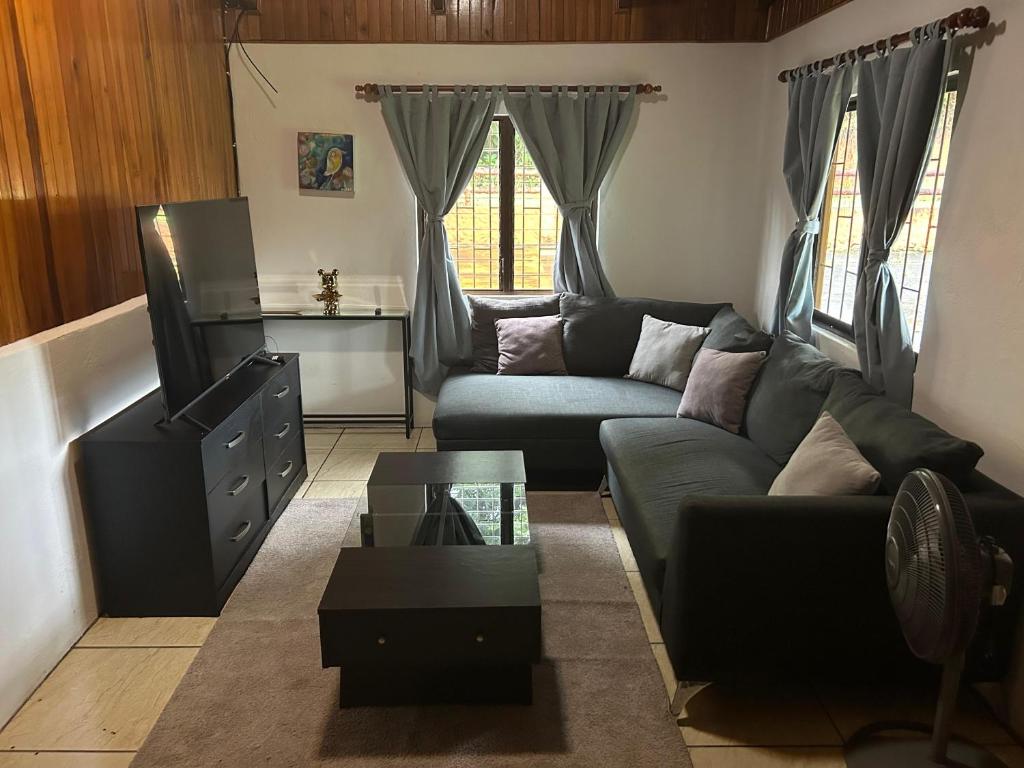 una sala de estar con un sofá y una mesa en Peaceful Jungle Home, River Access, Arenal Views, en El Castillo de La Fortuna