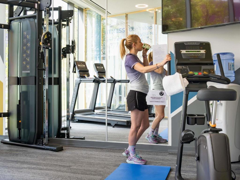 Una mujer parada en una cinta de correr en un gimnasio en Novotel Suites Luxembourg, en Luxemburgo
