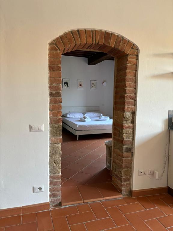 1 dormitorio con 1 cama y un arco de ladrillo en Maremma Castle Apartament, en Montemerano