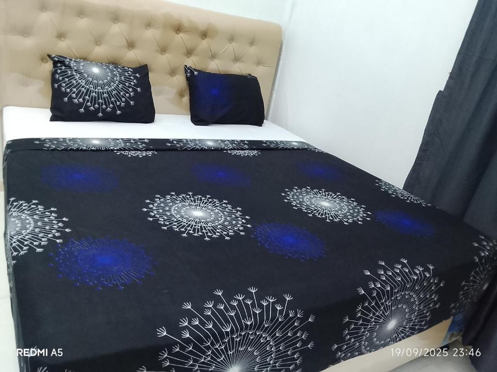 a bed with a black and white comforter and pillows at Wisma sane in Teratakairhitam