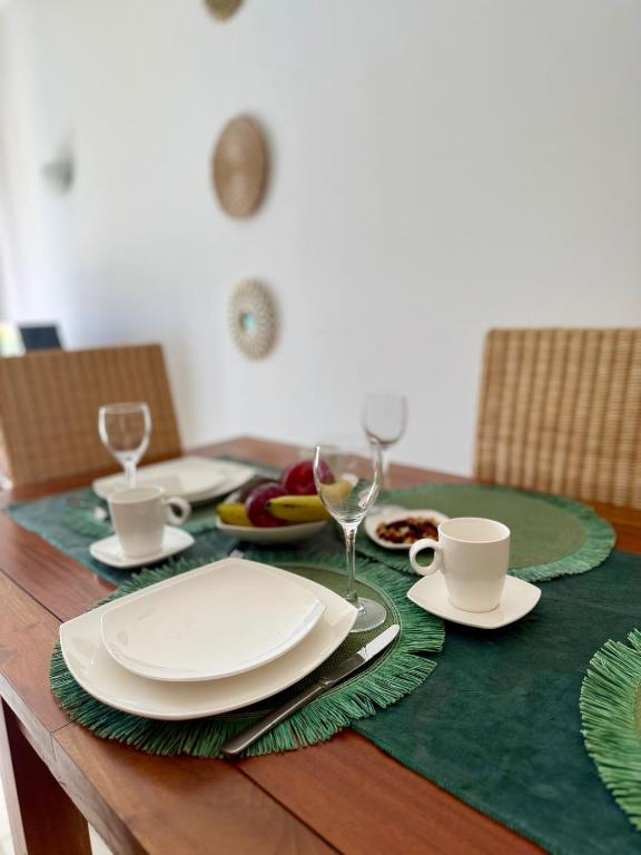 ein Holztisch mit weißen Tellern und Gläsern darauf in der Unterkunft Studio with pool in Santa Maria