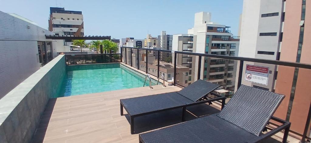 einen Balkon mit 2 Stühlen und einen Pool auf einem Gebäude in der Unterkunft Siberian Flat 204 Intermares in Cabedelo