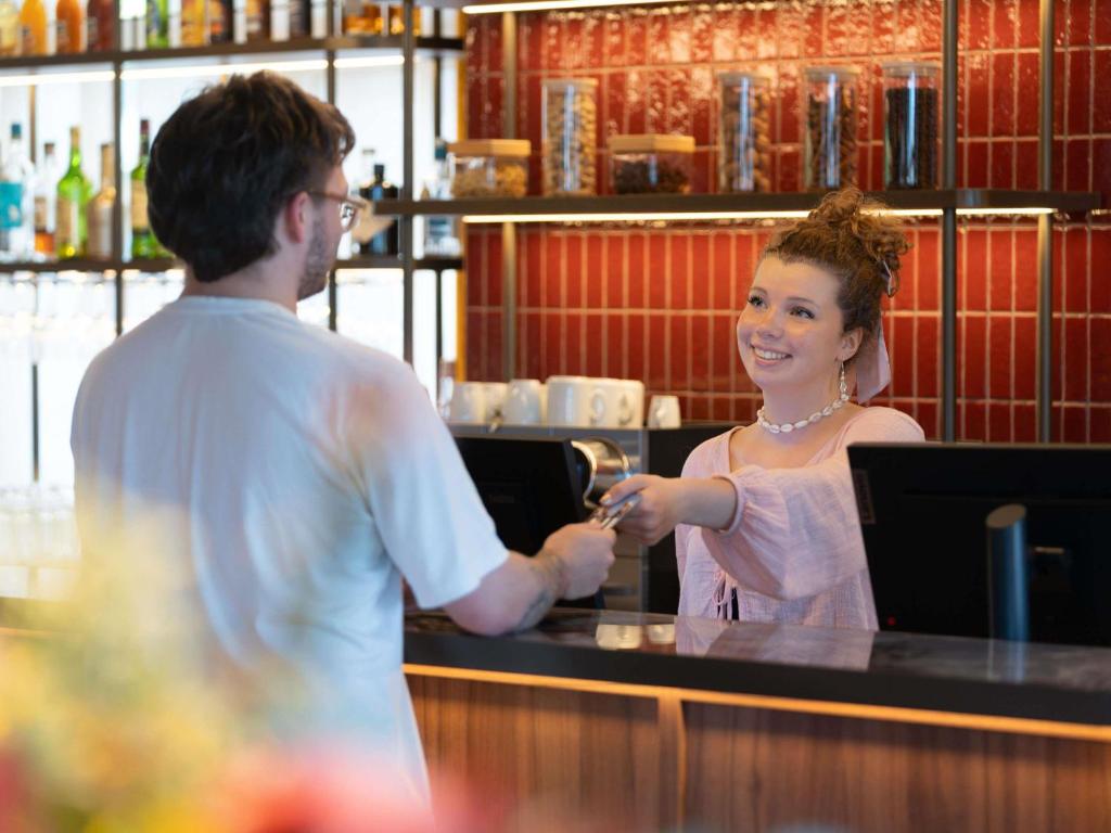 un homme et une femme debout à un comptoir dans l'établissement Novotel Nantes Centre Bord de Loire, à Nantes
