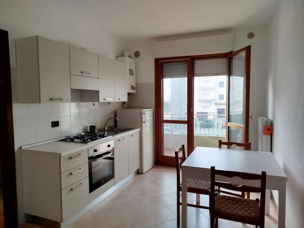 eine Küche mit weißen Schränken, einem Tisch und einem Esszimmer in der Unterkunft Cozy studio with pool in Caorle in Caorle