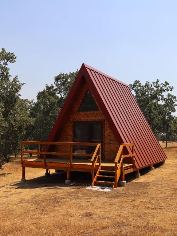 Una pequeña cabaña de troncos con techo rojo en El Roble Glamping - Cabaña Alpina Familiar, en Lagunilla
