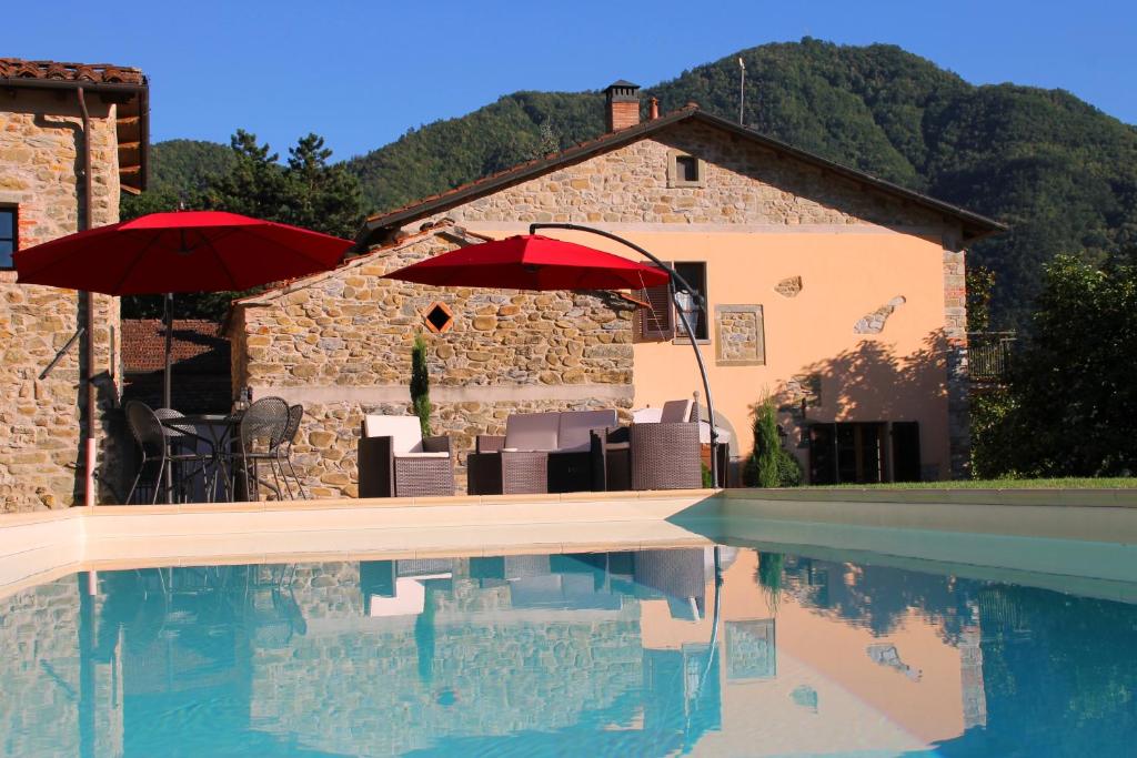 a pool with chairs and umbrellas next to a building at Agriturismo I Chiosi in Comano