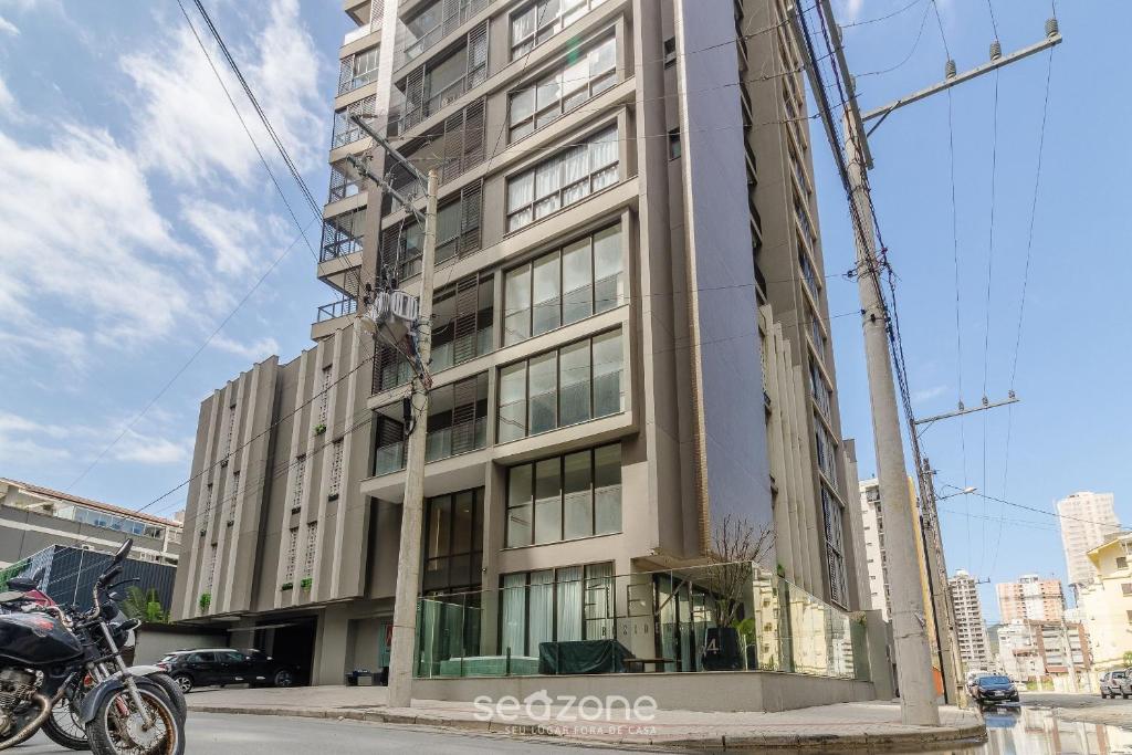 a tall building with a motorcycle parked in front of it at Apartamentos Bem Equipados a 100 m da Praia - EVR in Perequê