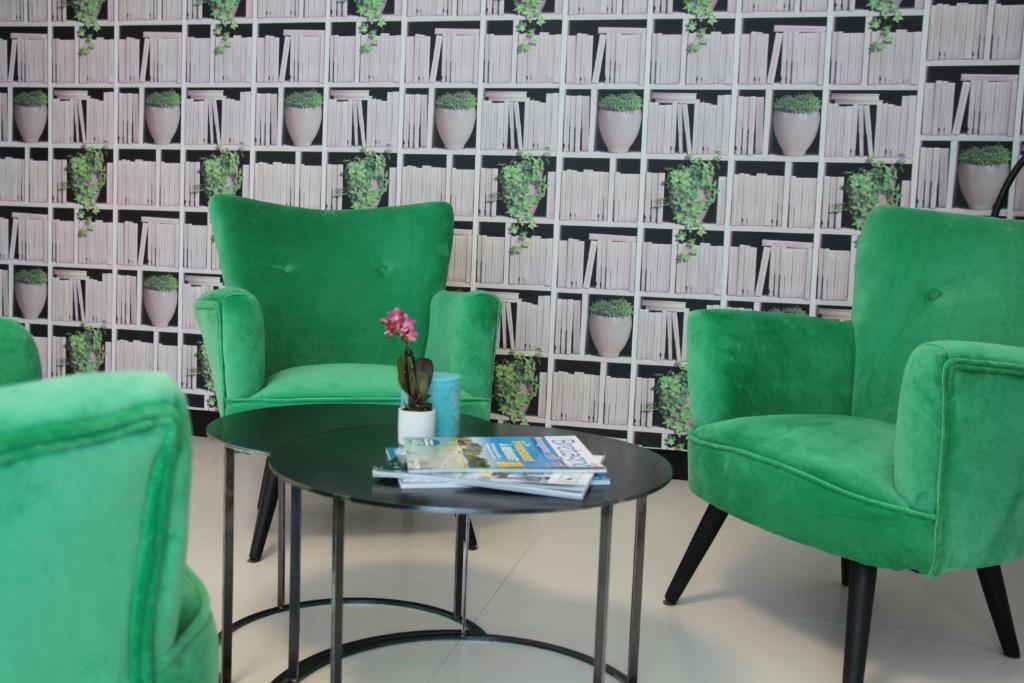 a room with two green chairs and a table at Le Cornouaille Hotel & Spa in Bénodet
